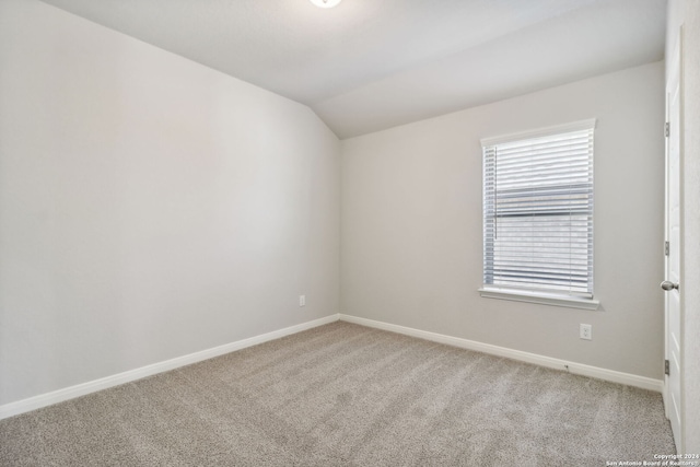 carpeted empty room with lofted ceiling and baseboards