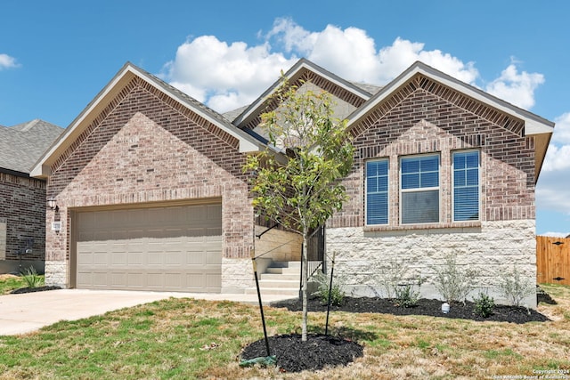 view of front facade with a garage, driveway, brick siding, and a front yard