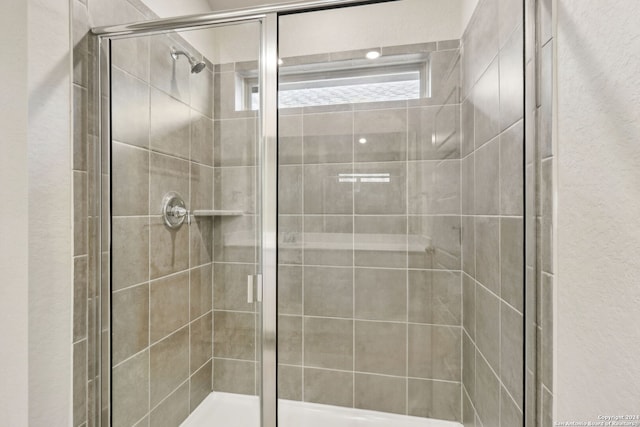 bathroom featuring tiled shower and a textured wall