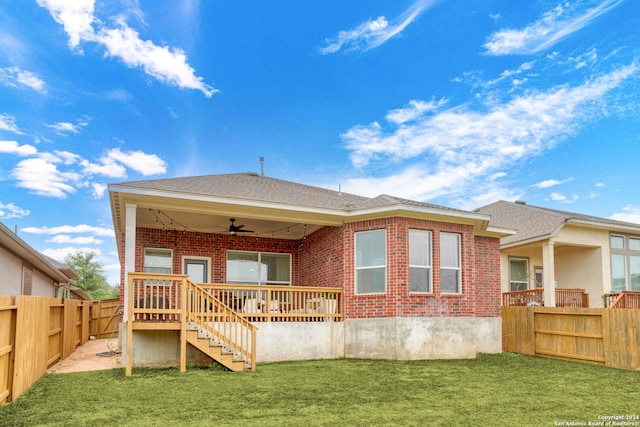 back of property featuring a lawn, a wooden deck, and ceiling fan