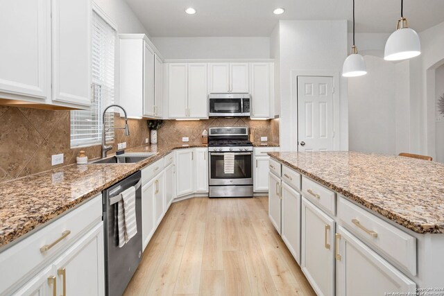 kitchen with white cabinetry, sink, hanging light fixtures, stainless steel appliances, and light hardwood / wood-style floors