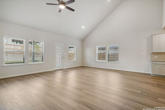 unfurnished living room with high vaulted ceiling, ceiling fan, and light wood-type flooring