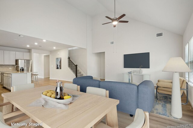 dining area featuring ceiling fan, light hardwood / wood-style flooring, and high vaulted ceiling