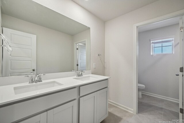 bathroom with toilet, vanity, and tile patterned floors