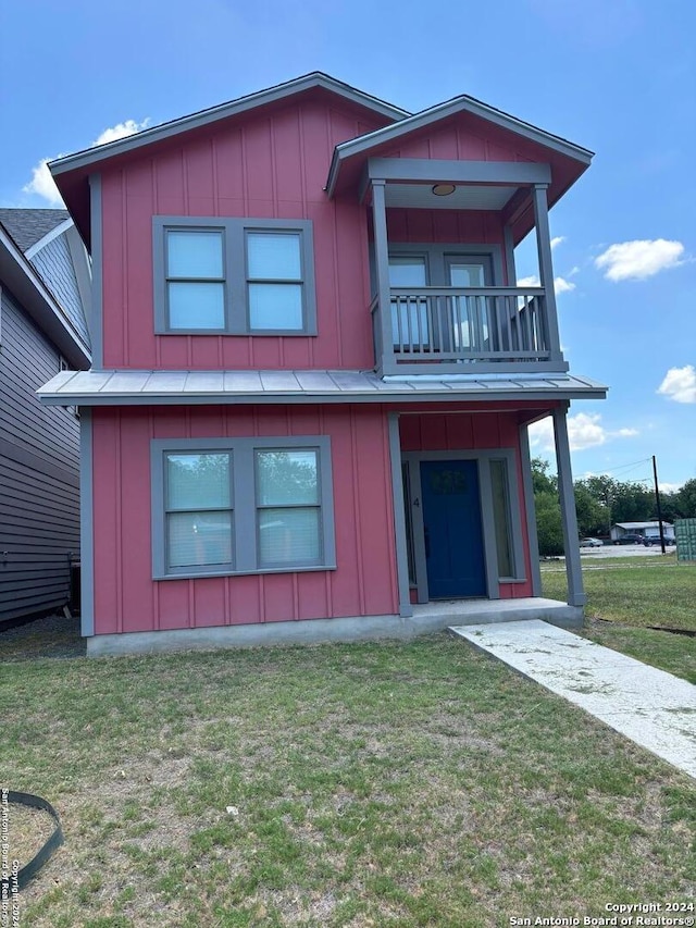 view of front of house featuring a balcony and a front lawn