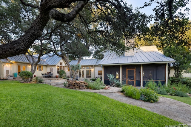 view of front of home with a sunroom and a front lawn