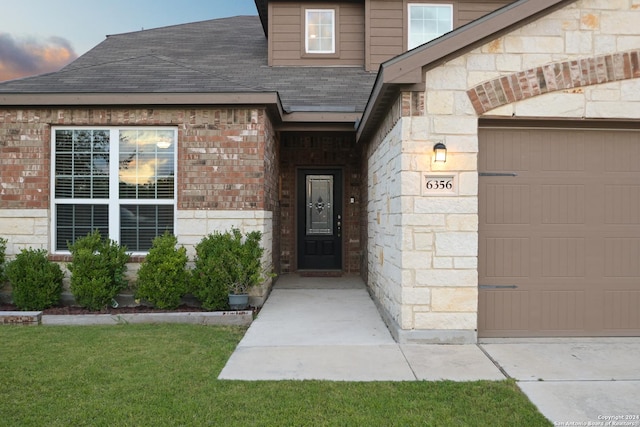 exterior entry at dusk featuring a garage