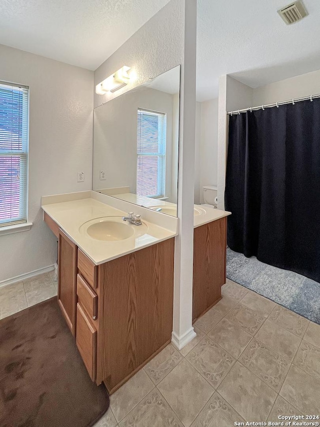 bathroom featuring a textured ceiling, vanity, toilet, and tile patterned floors