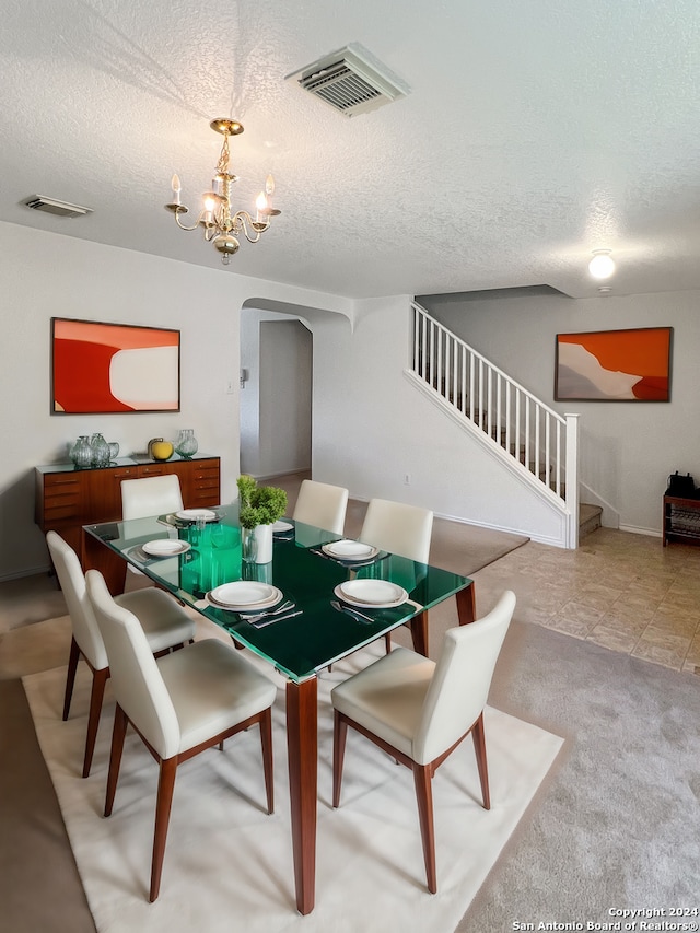 tiled dining space featuring a textured ceiling and an inviting chandelier