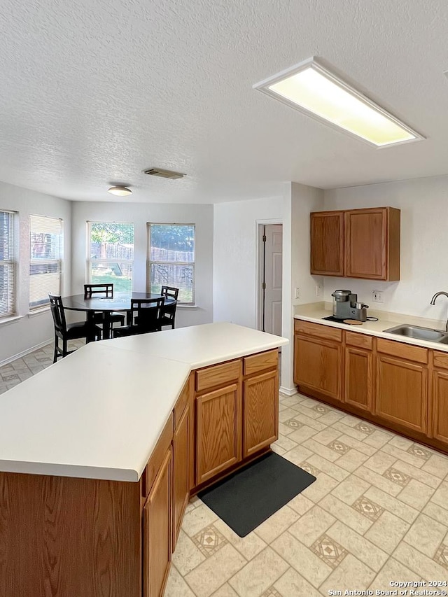 kitchen featuring a textured ceiling, a center island, and sink