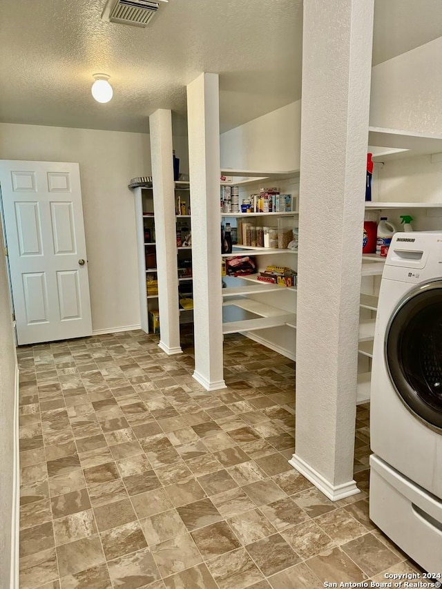 laundry area featuring a textured ceiling and washer / dryer