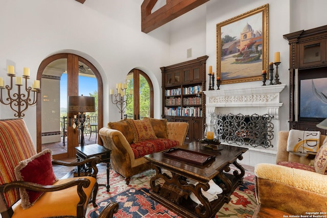 living room with french doors, a towering ceiling, and beam ceiling