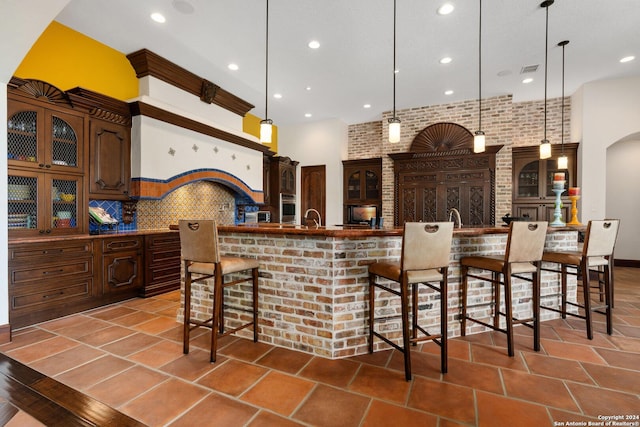 kitchen with a large island, brick wall, pendant lighting, decorative backsplash, and a breakfast bar