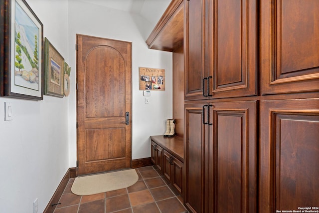 mudroom with dark tile patterned flooring and vaulted ceiling