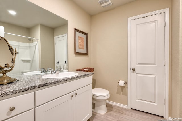 bathroom with hardwood / wood-style floors, vanity, toilet, and walk in shower