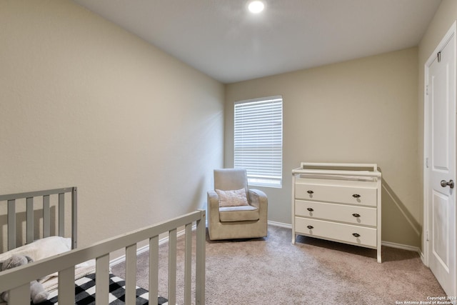 bedroom with a crib, light colored carpet, and multiple windows