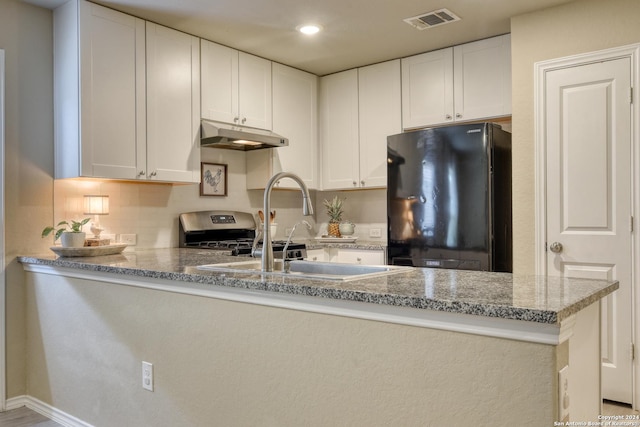 kitchen featuring light stone countertops, sink, black fridge, kitchen peninsula, and white cabinets