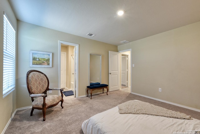 bedroom featuring light carpet and connected bathroom