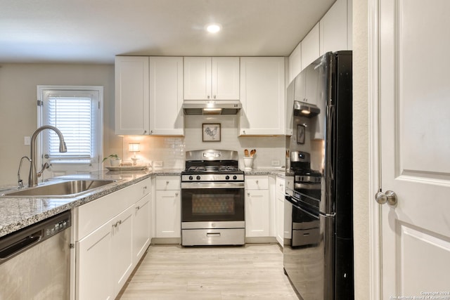 kitchen featuring white cabinets, sink, tasteful backsplash, light stone counters, and stainless steel appliances