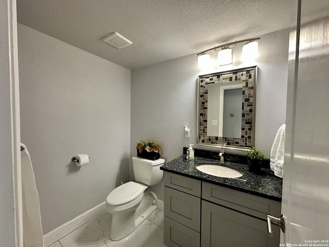 bathroom with a textured ceiling, toilet, and vanity