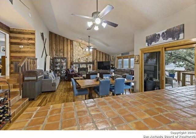 tiled dining area with wood walls, plenty of natural light, ceiling fan, and a fireplace