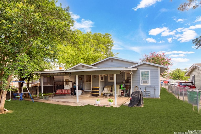 back of house with a playground, a patio area, and a lawn