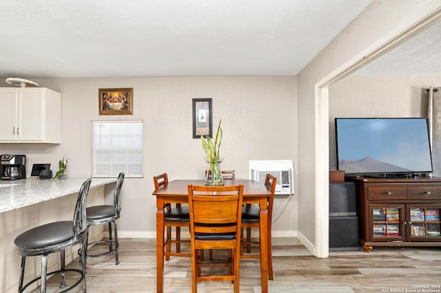 dining space featuring light wood-type flooring and an AC wall unit