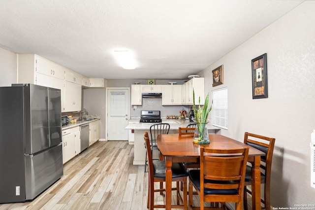 dining space with a textured ceiling, light wood-type flooring, and sink