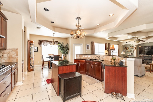 kitchen featuring ceiling fan with notable chandelier, decorative light fixtures, a kitchen island, and tasteful backsplash