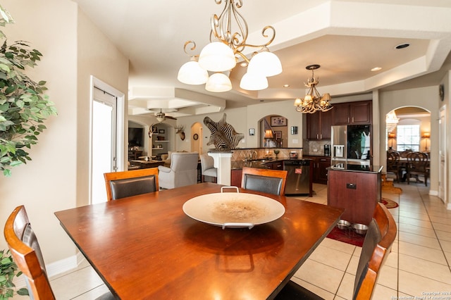 dining space with sink, light tile patterned floors, and ceiling fan with notable chandelier