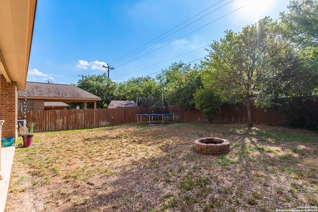 view of yard featuring a trampoline and an outdoor fire pit