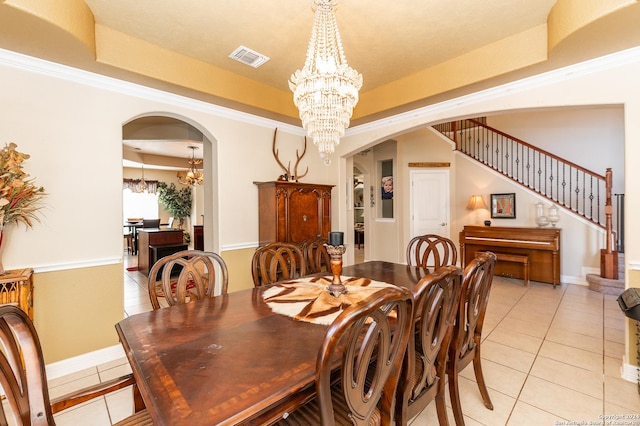 tiled dining area with a tray ceiling, an inviting chandelier, and ornamental molding