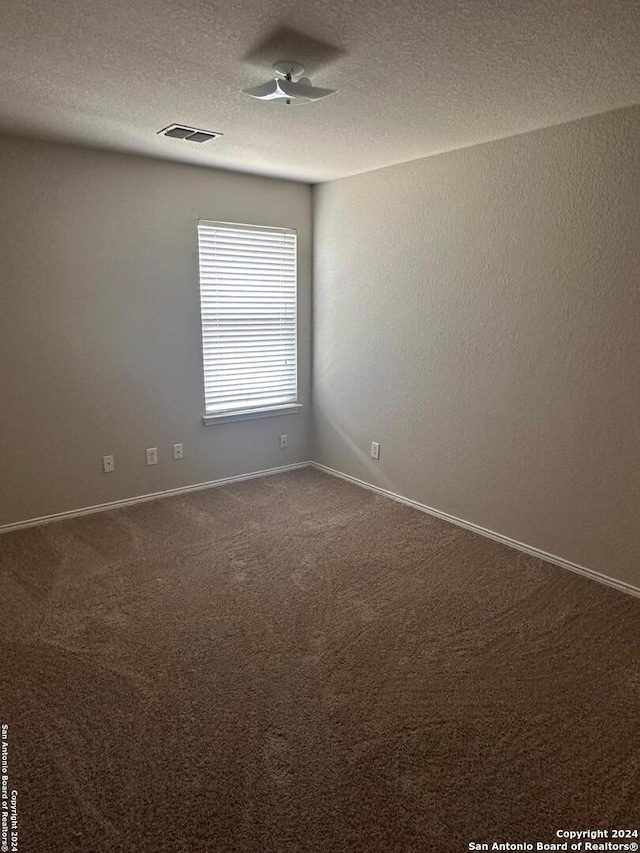 spare room featuring carpet floors, a textured ceiling, and ceiling fan