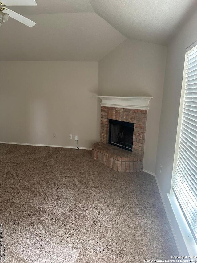 unfurnished living room featuring a fireplace, carpet, a textured ceiling, lofted ceiling, and ceiling fan