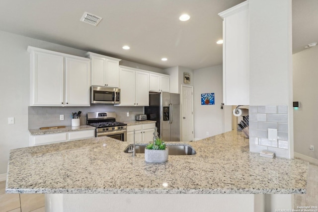 kitchen with white cabinets, light stone counters, kitchen peninsula, and appliances with stainless steel finishes