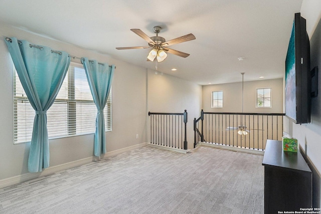 carpeted spare room featuring plenty of natural light and ceiling fan