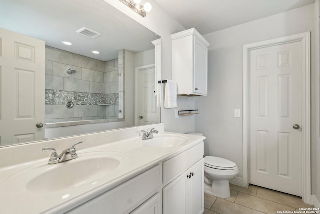 bathroom featuring toilet, a tile shower, vanity, and tile patterned floors