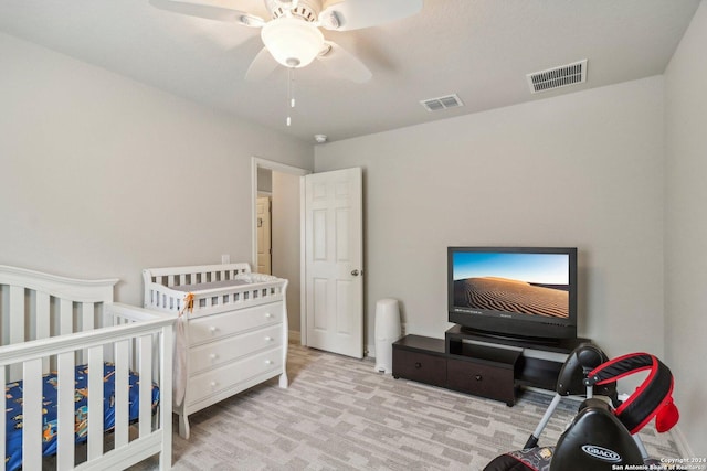 carpeted bedroom with ceiling fan and a crib