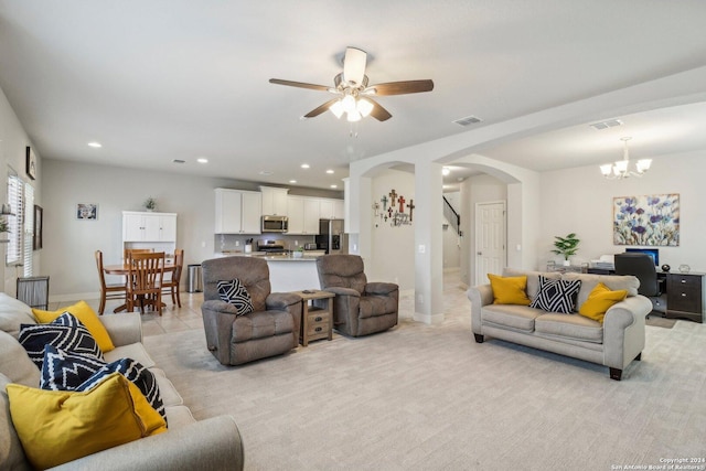 living room featuring ceiling fan with notable chandelier