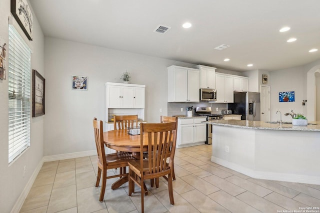 kitchen featuring light stone countertops, light tile patterned floors, stainless steel appliances, and white cabinetry