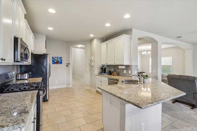 kitchen with light stone countertops, sink, white cabinetry, and stainless steel appliances