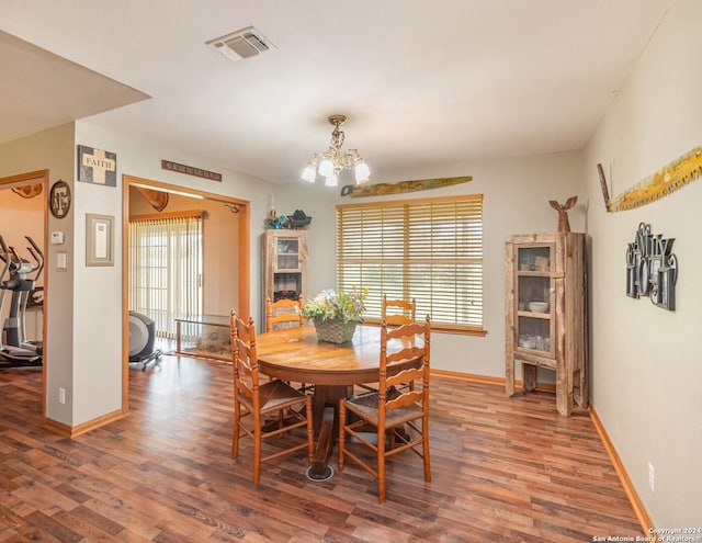 dining area with wood-type flooring and an inviting chandelier