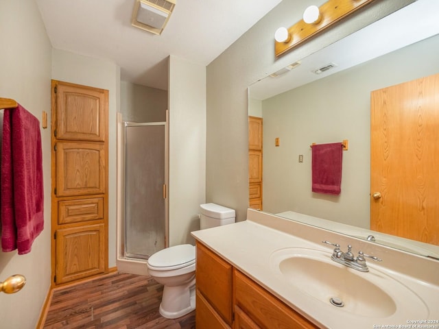 bathroom featuring toilet, vanity, an enclosed shower, and hardwood / wood-style flooring