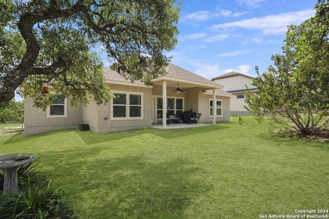 back of property with ceiling fan, a patio area, and a yard