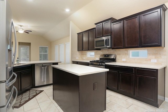 kitchen featuring kitchen peninsula, appliances with stainless steel finishes, light tile patterned floors, a center island, and lofted ceiling