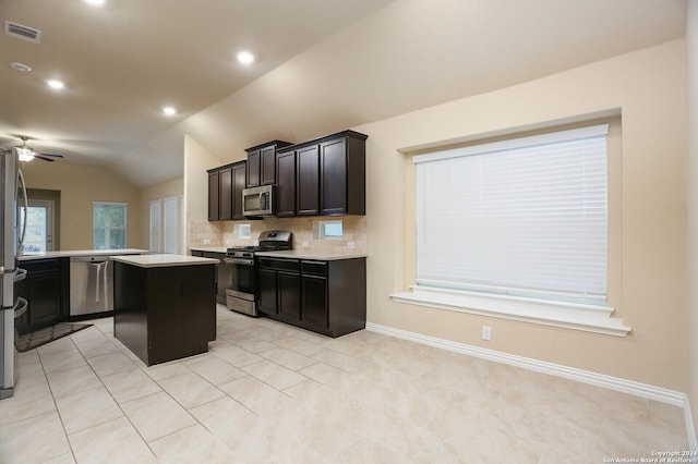 kitchen with tasteful backsplash, stainless steel appliances, ceiling fan, a kitchen island, and lofted ceiling