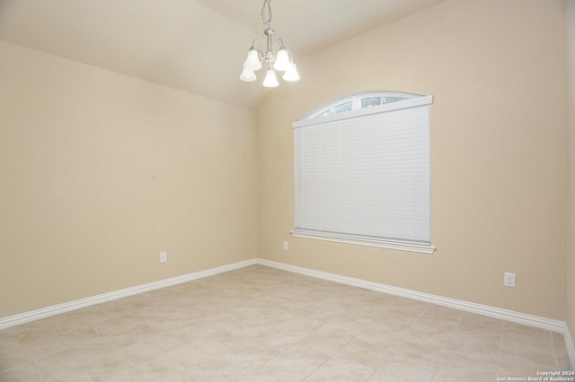 spare room featuring a notable chandelier and vaulted ceiling