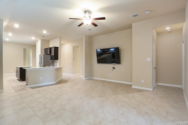 unfurnished living room with ceiling fan, sink, and light tile patterned flooring