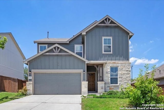 craftsman-style house featuring stone siding, board and batten siding, concrete driveway, and fence