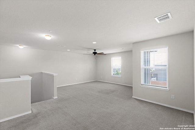 carpeted spare room featuring a textured ceiling and ceiling fan